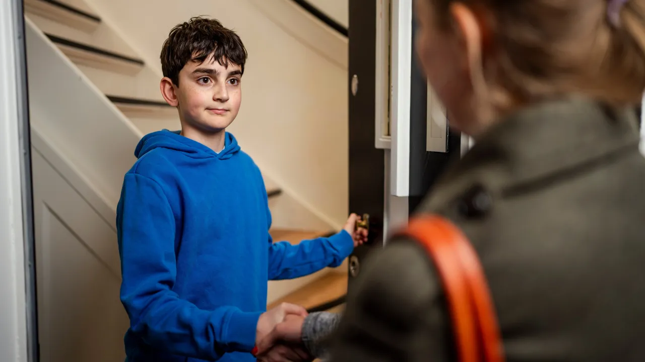 jongen in deuropening geeft vrouw hand
