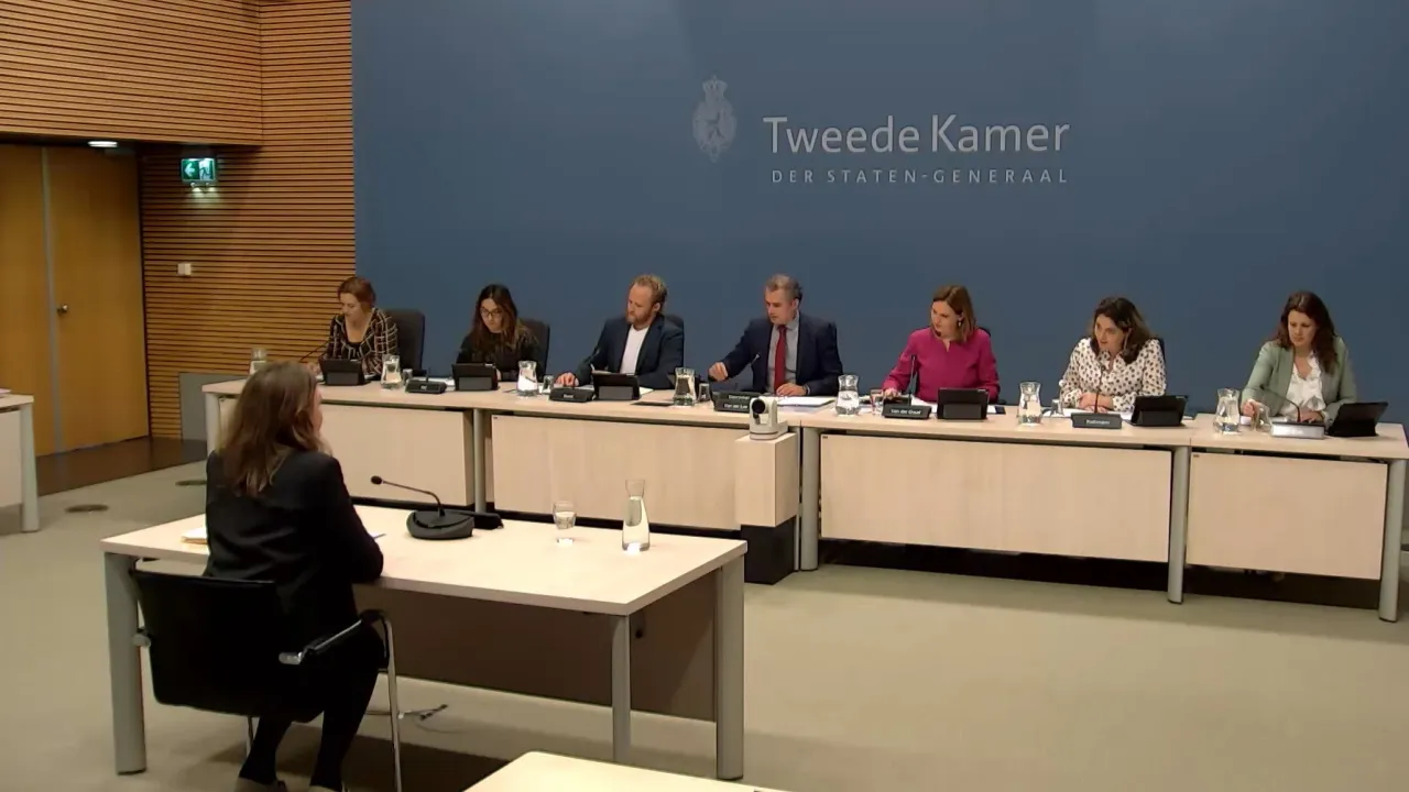 Kinderombudsvrouw Margrite Kalverboer zit in een zaal. Voor haar zitten leden van de enquêtecommissie leden van de 