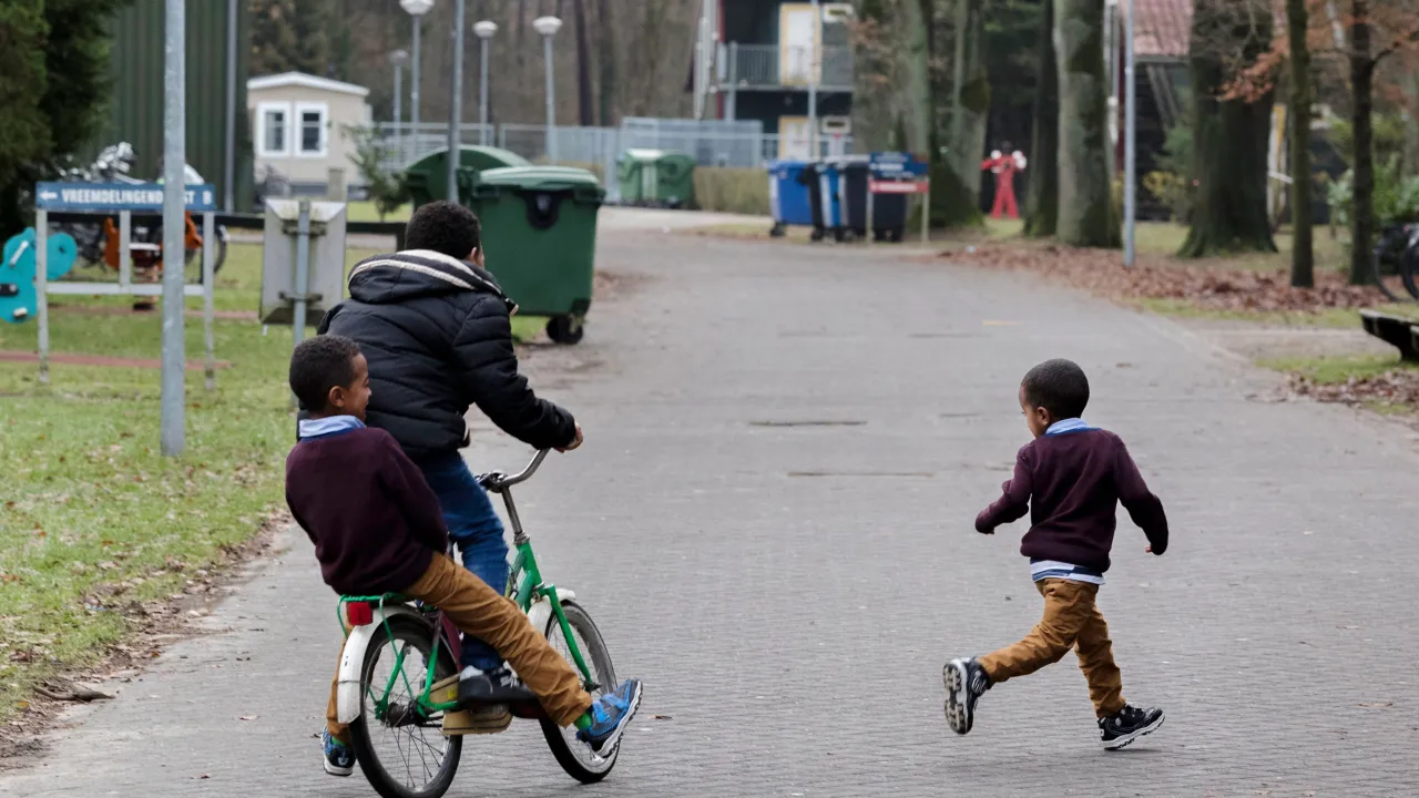 jonge kinderen spelen op het AZC terrein. Ze rijden op fietsjes