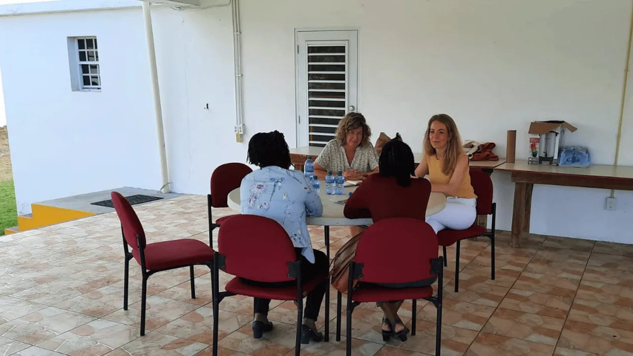 Vier vrouwen zijn in gesprek. Ze zitten aan tafel