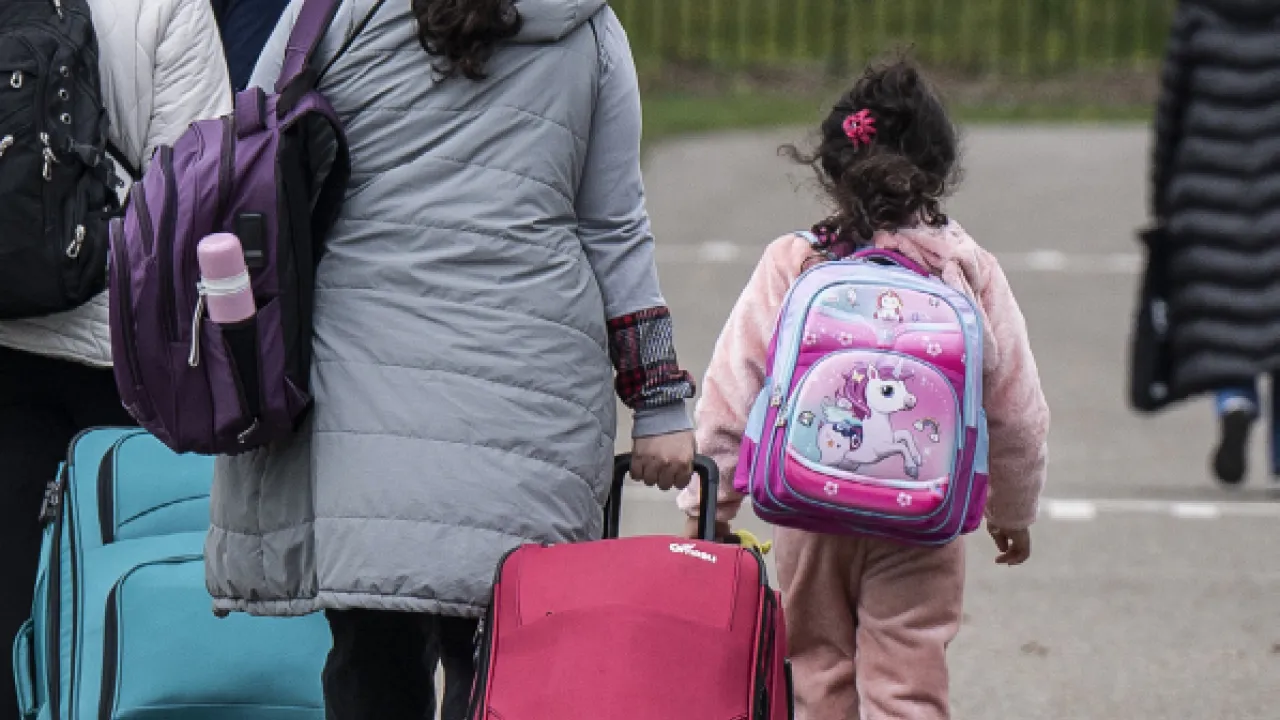 Vrouw en kind lopen met koffer over straat