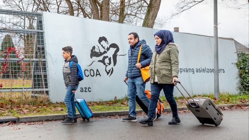 Azielzoekers (man, vrouw, kind) lopen naar AZC