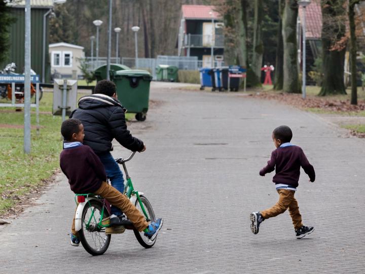 jonge kinderen spelen op het AZC terrein. Ze rijden op fietsjes