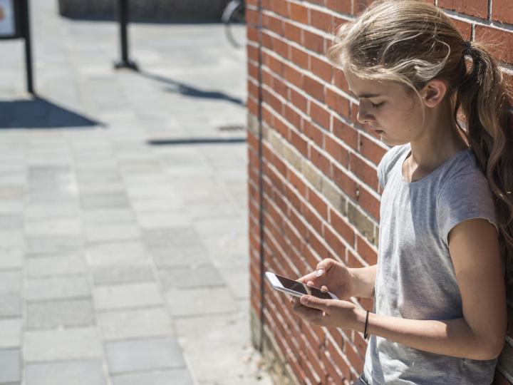 Een meisje met een telefoon in haar hand. 