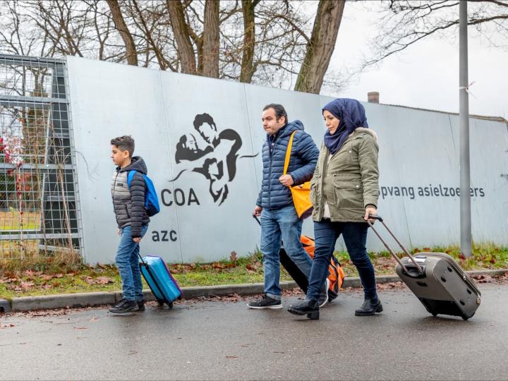 Azielzoekers (man, vrouw, kind) lopen naar AZC